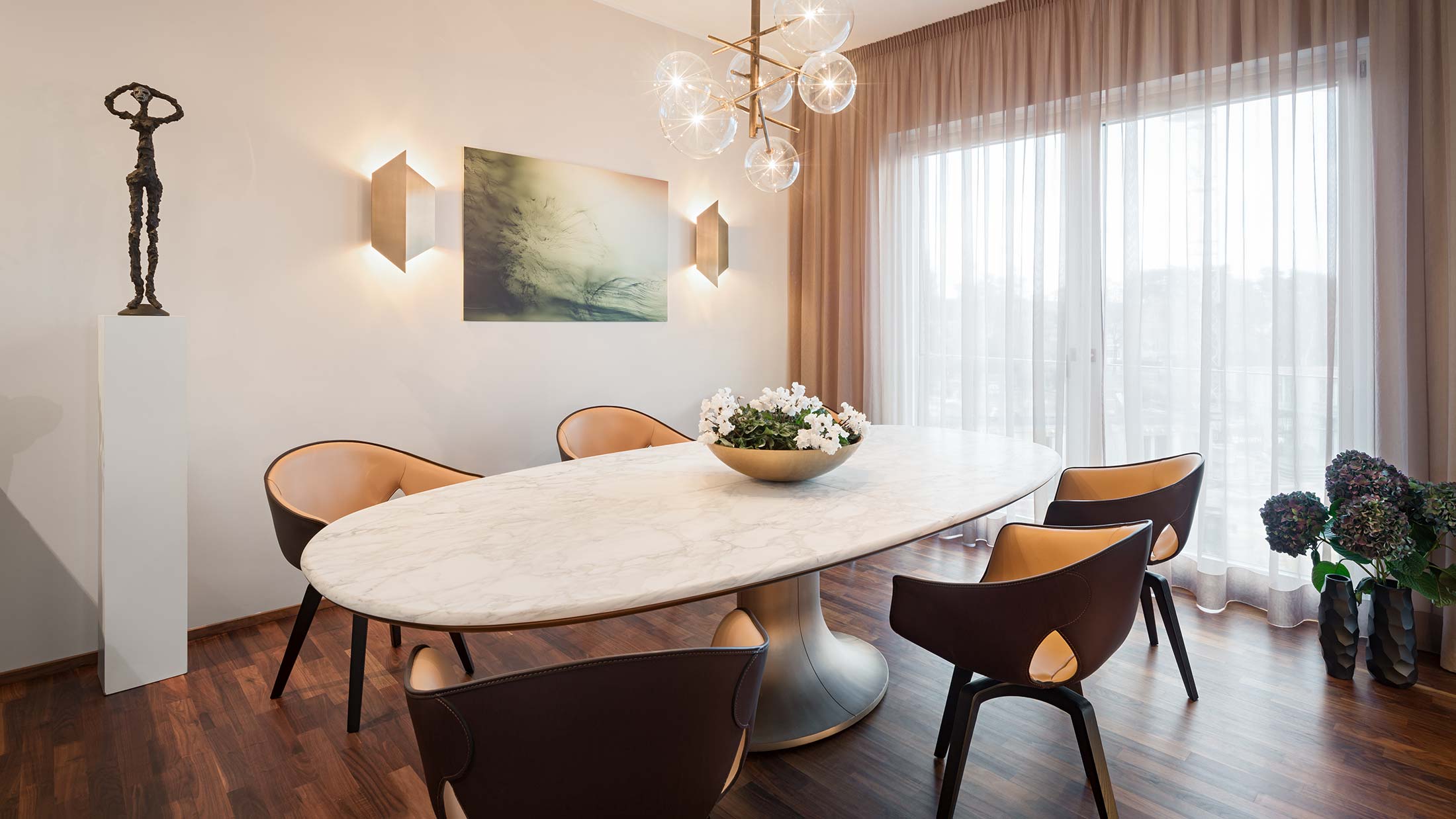 Penthouse Fünf Morgen: Esszimmer Tisch mit markantem Bronzefuß und Platte aus edlem Marmor Calacatta Oro